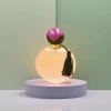 The pink round perfume bottle is equipped with a purple-black double-color ball-shaped cap and black tassels for decoration Specification image
